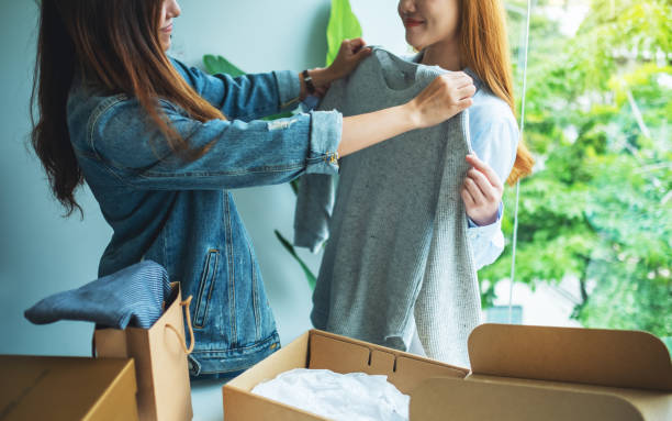 istock Two young women receiving a postal parcel box and try on clothes at home 1265972111