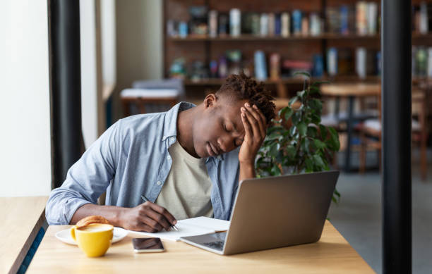 istock Exhausted black man studying online on laptop computer at cozy coffee shop 1265972513
