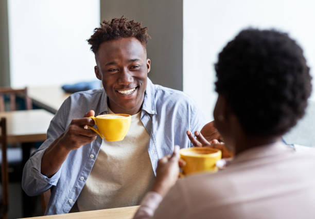 istock Handsome black guy with his girlfriend drinking coffee together at city cafe 1265972522