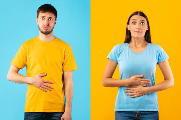 giovane femmina e maschio che si toccano lo stomaco - women stomachache abdomen stomach foto e immagini stock