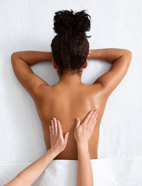 Therapist massaging african woman back, top view Unrecognizable therapist massaging african american woman back on white, top view massage stock pictures, royalty-free photos & images