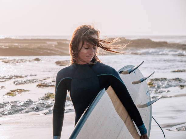 istock Surfer woman on the beach at sunrise 1265985779
