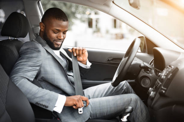 Handsome black businessman fasten seat belt in his car Handsome black businessman fasten seat belt in his car, ready to go to office seat belt photos stock pictures, royalty-free photos & images