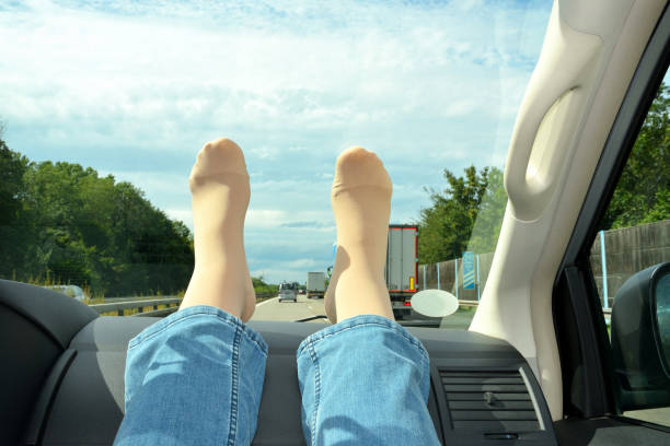 Legs in compression stockings rest on the car's torpedo. Concept for prevention of varicose veins and deep vein thrombosis during long journeys. stock photo