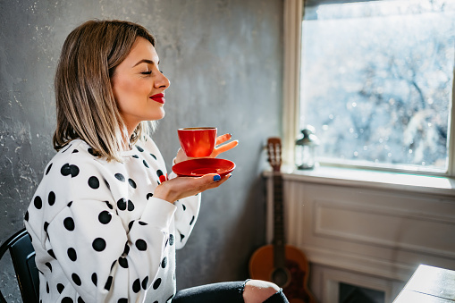 Portrait of beautiful young Caucasian smiling woman enjoying in coffee.