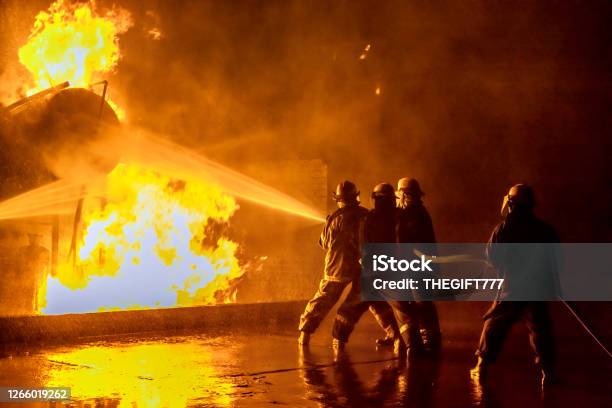 Firefighters Extinguishing An Industrial Fire Stock Photo - Download Image Now - Firefighter, Fire - Natural Phenomenon, Accidents and Disasters