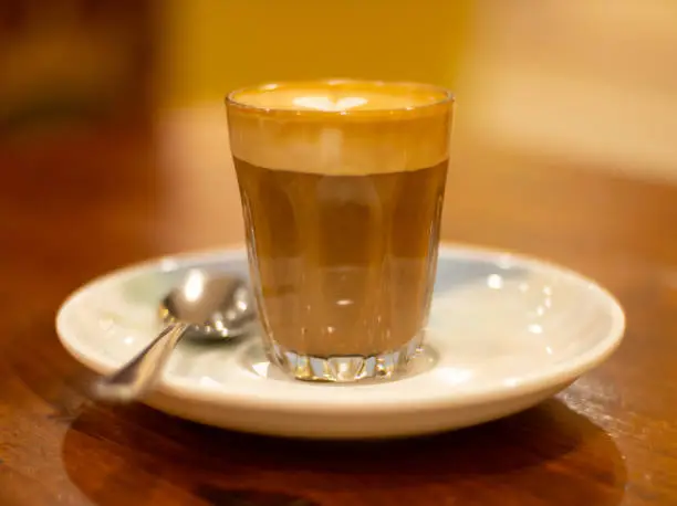 Glass of Coffee Piccolo Latte on a wooden table