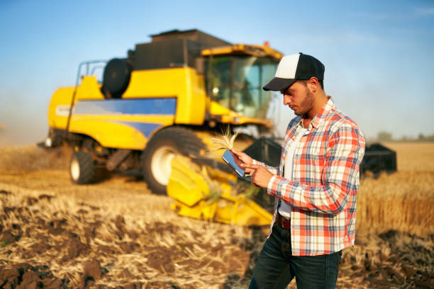 istock Precision farming. Farmer holding tablet for combine harvester guidance and control with modern automation system. Agronomist using online data management software generating yield maps at wheat field 1266027700