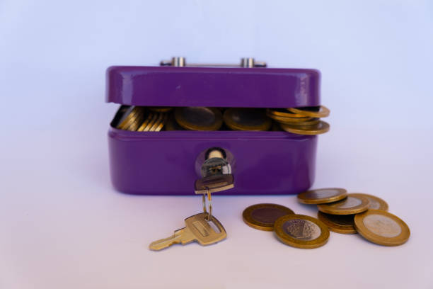 The Turkish metal shines overflowing from the piggy bank. The safe with the key is purple in color, white background