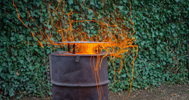 istock Life hack. Metal barrel with lid for burning branches in garden. Barrel on blurred background wall of ordinary ivy or ivy English. Selective focus. Ecology. Fire safety. 1266041393