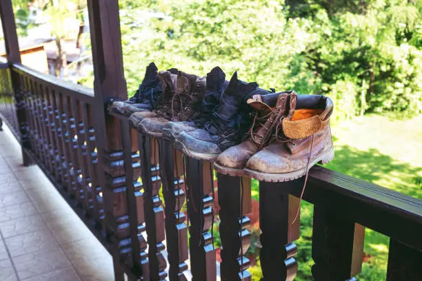 June 13, 2020 - Pieniny, Poland:  dirty family hiking boots drying up in a row on a railing in a balcony - wide angle, copy space.