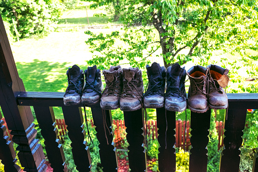 Botas de senderismo familiar sucio secándose en una fila en una barandilla en un balcón - gran angular, copiar espacio. photo