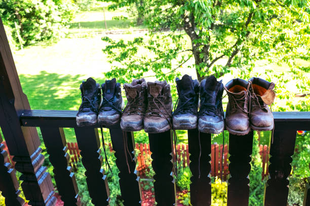 Dirty family hiking boots drying up in a row on a railing in a balcony - wide angle, copy space. stock photo