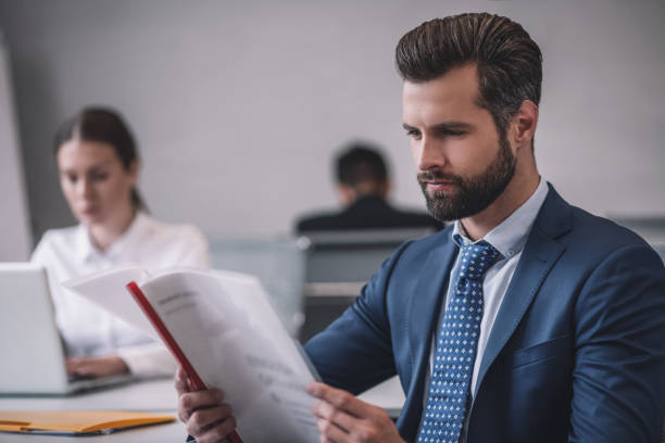 istock Bearded man with document woman behind laptop 1266062412