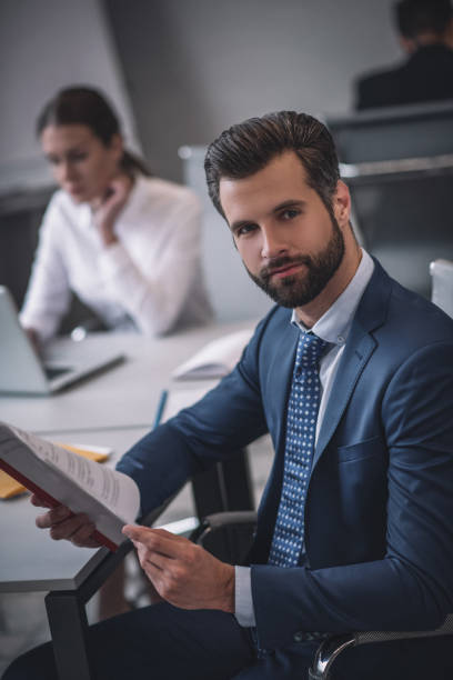 istock Young bearded man in tie and suit with documents 1266062417