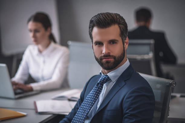 istock Attractive man sitting at table in office with colleagues 1266062425