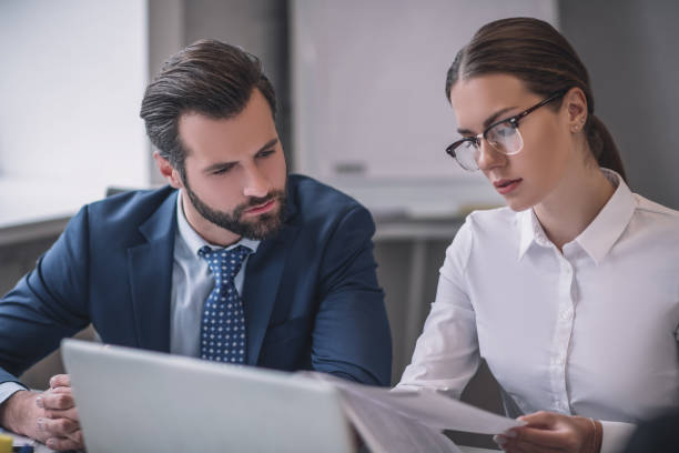 istock Bearded man and woman in glasses looking at documents 1266062466