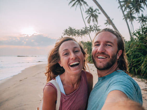 istock Young couple taking mobile phone selfie on tropical beach at sunset 1266076702