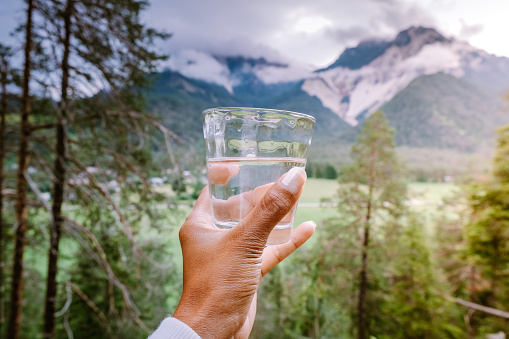 glass of water in hand looking out over mountains, drinking water , hand glass water