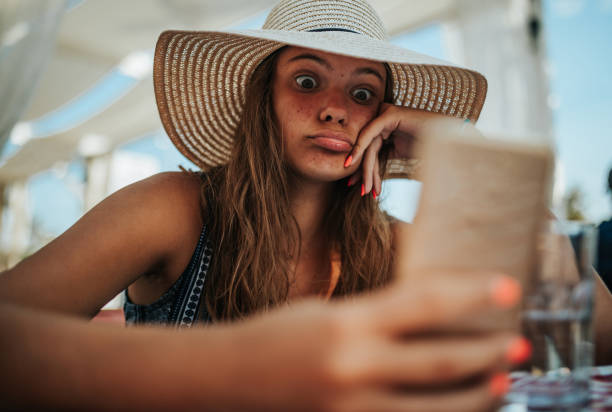 istock Girl looking at her front camera on mobile phone 1266078323