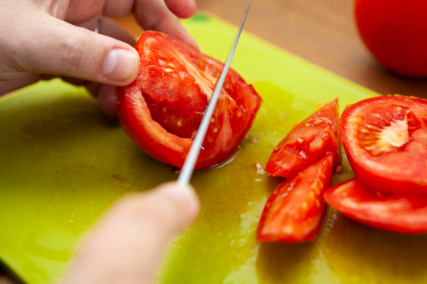 istock Knife roughly chopping a tomato on a green chopping board 1266078627