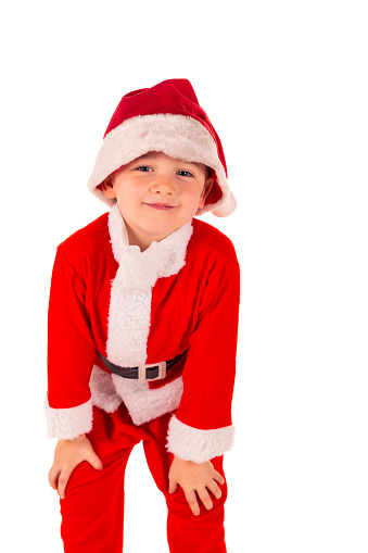 Portrait of a cute little boy (4 years old) standing up, hands on knees wearing a red Santa Claus costume with a Santa hat. Christmas and holidays theme isolated on white
