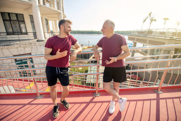 istock Yound male and grey-haired male leaning on bridge railing, resting during running 1266078798