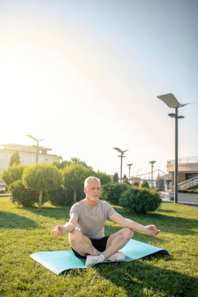 istock Grey-haired man meditating in lotus pose with hands in Gyan mudra 1266078850
