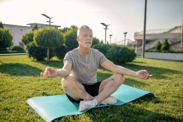 istock Grey-haired man sitting in lotus pose with hands in Gyan mudra 1266078853