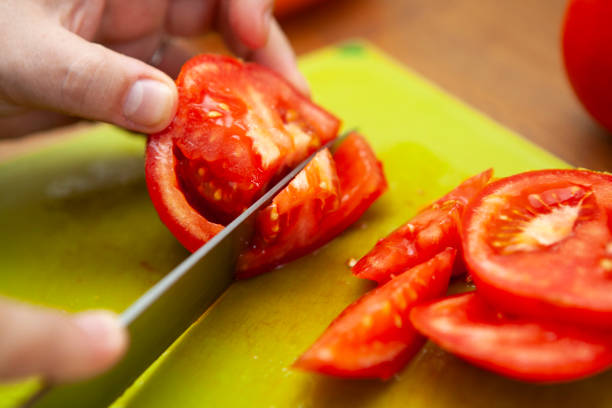 istock Knife roughly chopping a tomato on a green chopping board 1266078883