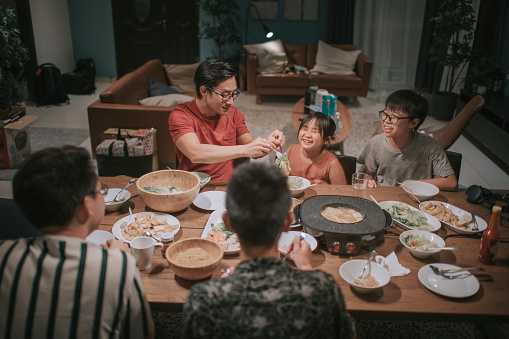 an asian chinese families and friends having night dinner gathering at home with traditional chinese steamboat dishes