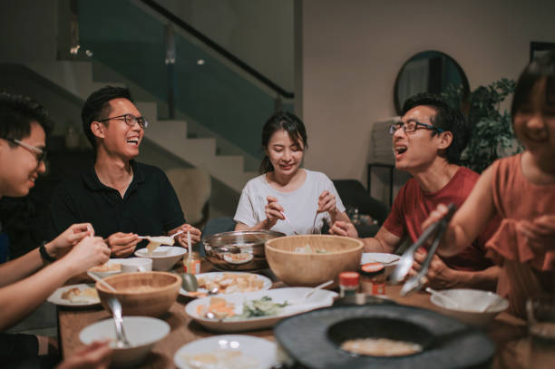 uma família chinesa asiática e amigos tendo jantar noturno reunindo em casa com pratos tradicionais chineses de barco a vapor - chinese ethnicity family togetherness happiness - fotografias e filmes do acervo