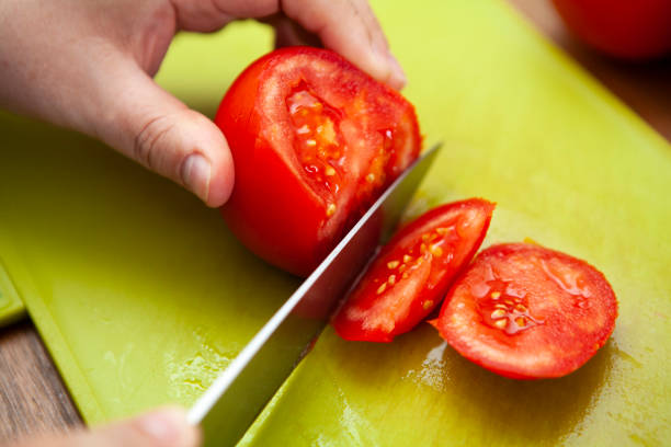 istock Knife roughly chopping a tomato on a green chopping board 1266083014