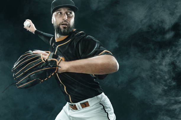 istock Baseball player with ball. Ballplayer on black background. 1266084181