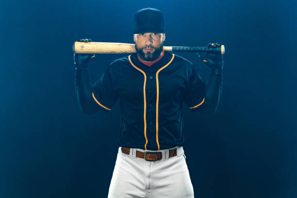 jugador de béisbol con bate en fondo oscuro. retrato de jugador. - men baseball baseball cap baseball bat fotografías e imágenes de stock