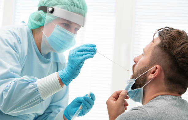 Doctor testing patient on possible coronavirus infection Doctor in a protective suit taking a throat and nasal swab from a patient to test for possible coronavirus infection cotton swab photos stock pictures, royalty-free photos & images