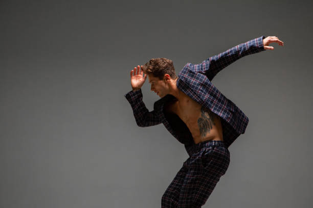istock Cool young guy dancer in suit dancing modern expressive dance in studio. Dance school poster. Dance lessons 1266086752
