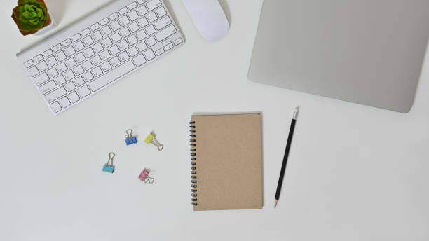 istock Modern workspace of white office table with laptop, keyboard, mouse, pencil and notebook. Top view. 1266087694