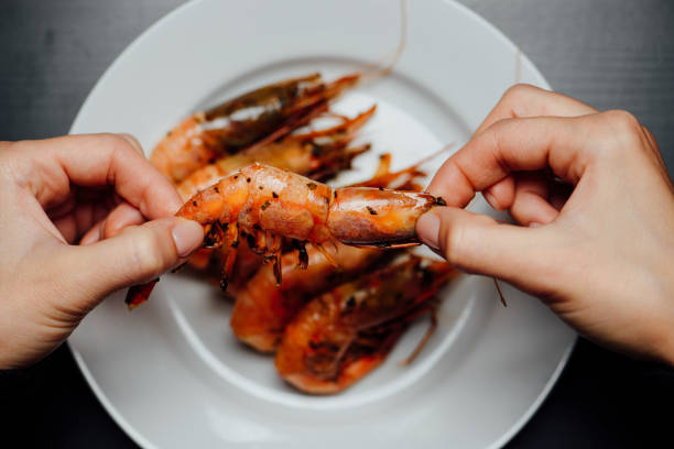 fried shrimps on a black background white plate with fried shrimps in the hands of a woman on a black background black tiger shrimp stock pictures, royalty-free photos & images