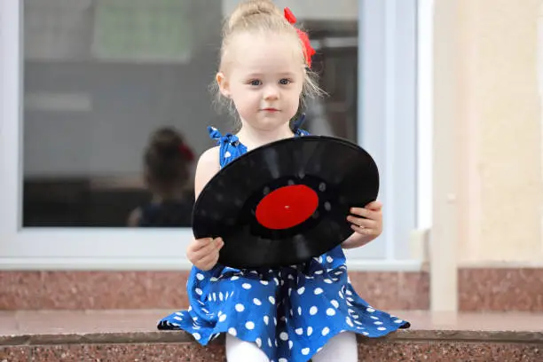 Photo of little girl sitting with records on the steps