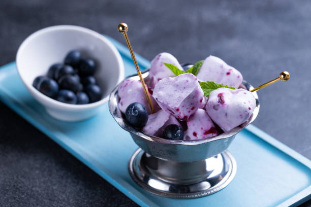 Frozen yogurt in a heart shape Frozen yogurt in a heart shape, Blueberries and froyo bites on black stone board frozen yoghurt stock pictures, royalty-free photos & images