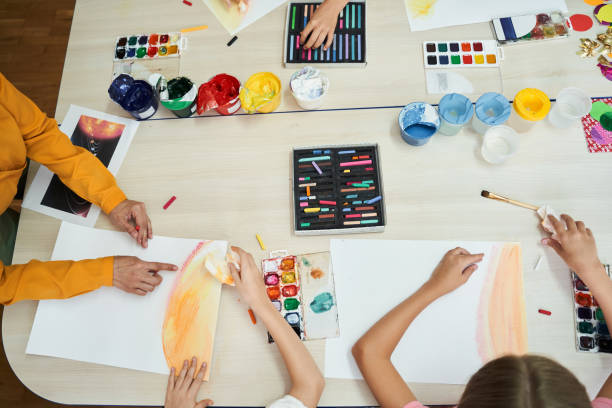 istock Children with tutor making pictures in class room 1266093146