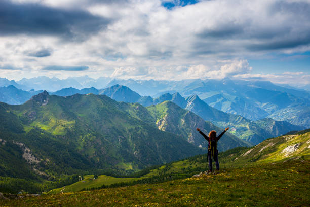istock Woman with backpack resting on mountain top, looking at view dramatic landscape valley summer activity fitness wellbeing freedom concept, rear view 1266095012