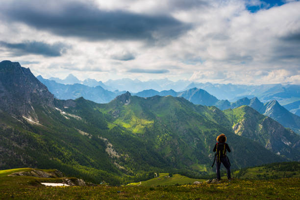 istock Woman with backpack resting on mountain top, looking at view dramatic landscape valley summer activity fitness wellbeing freedom concept, rear view 1266095047