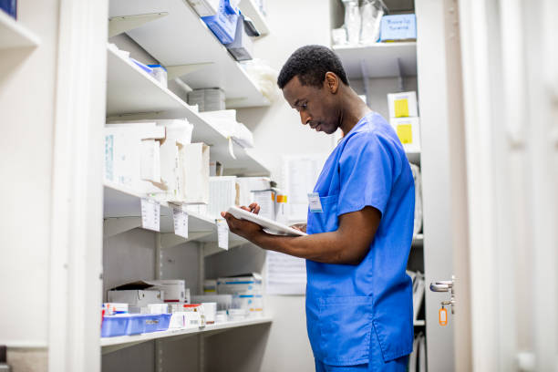 joven médico haciendo un inventario de suministros médicos en un armario del hospital - pharmacy medicine pharmacist storage room fotografías e imágenes de stock