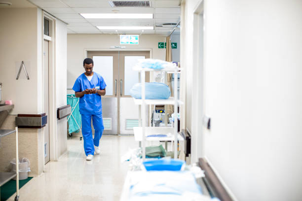 istock Young doctor checking his cellphone while walking along a hospital corridor 1266096646