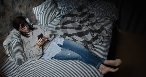 istock Woman is text messaging on her smart phone while lying on the sofa 1266096903