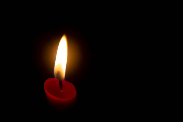 istock Red candle with yellow flame on black background 1266096967