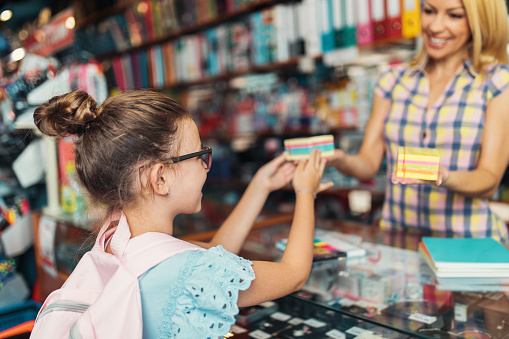 Happy mother with her daughter choosing and buying school supplies. Education and primary school preparations concept.