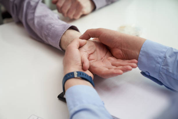 Wrist palpation as a part of hand examination Cropped photo of a doctor hands examining the wrist tendons of an elderly man during a medical check-up body shiver stock pictures, royalty-free photos & images